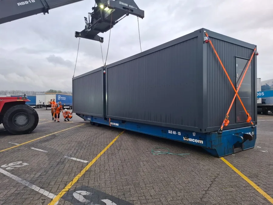 Ein Container wird auf dem Umschlagplatz per Reachstacker auf einen Trailer gesetzt.