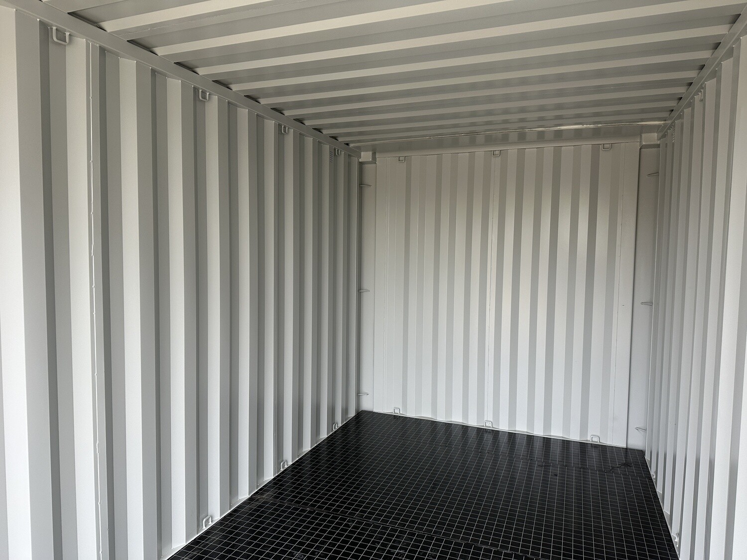 Innenansicht des 15 Fuß Lagercontainers mit hellen Wellblechwänden, Decke und schwarzem Gitterrostboden