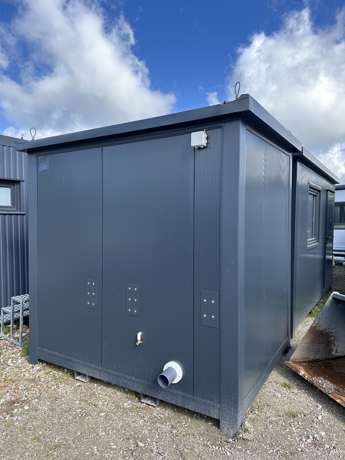 Rückwand des WC-Containers mit Lüftungsgitter, Wasserhahn, Abwasserstutzen und Kranösen am Dach
