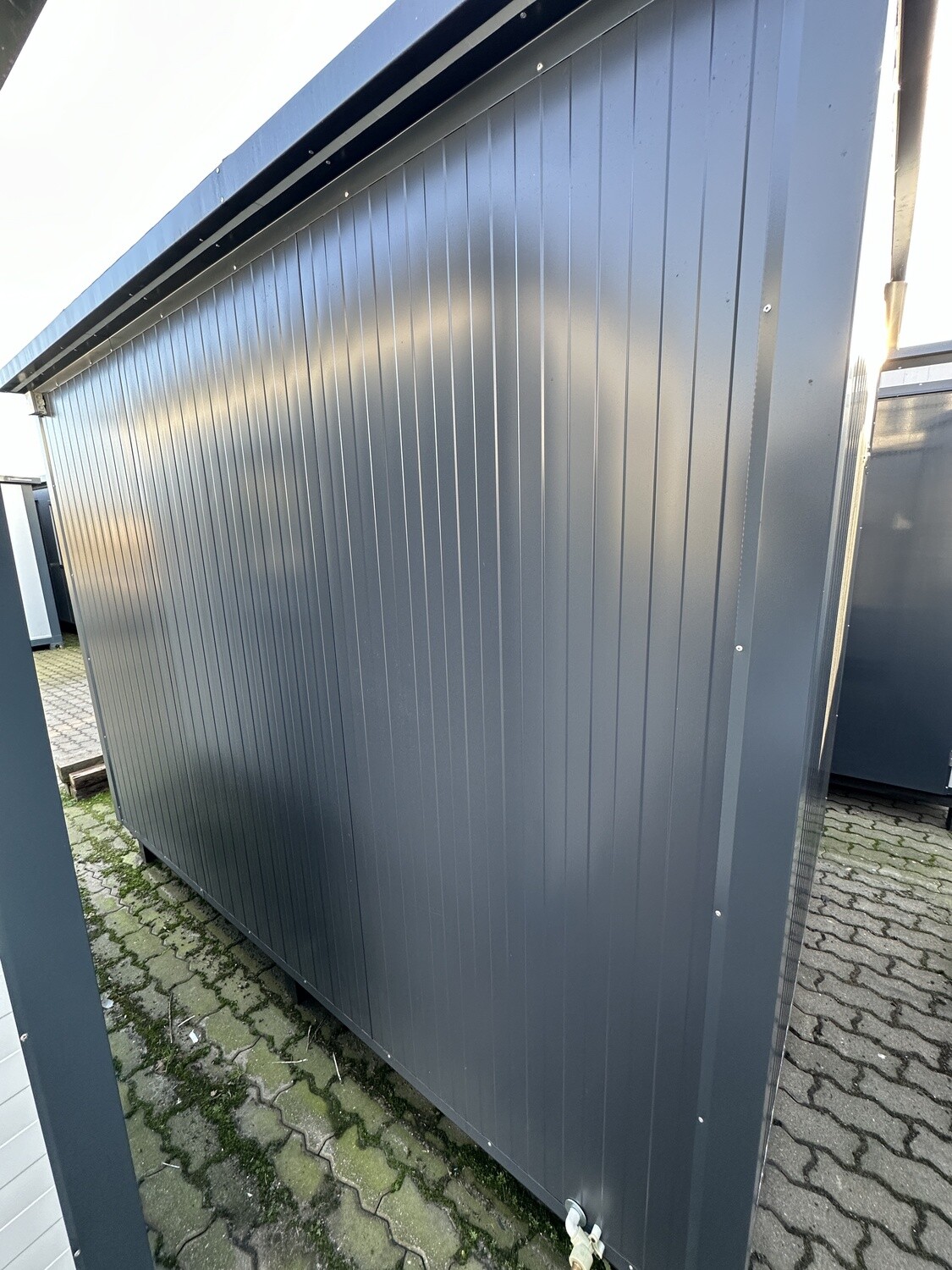 Geschlossene Längsseite des Doppel-WC Containers mit profilierter anthrazitfarbener Wandverkleidung