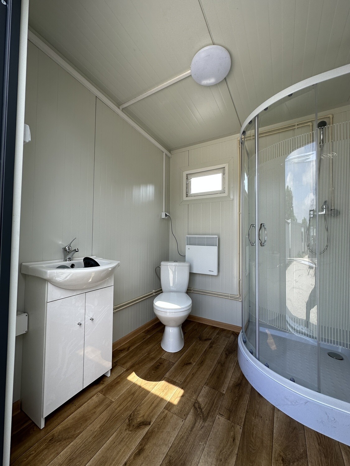 Kabine des Doppel-WC-Containers mit Waschtisch, WC, viertelrunder Dusche und Deckenleuchte