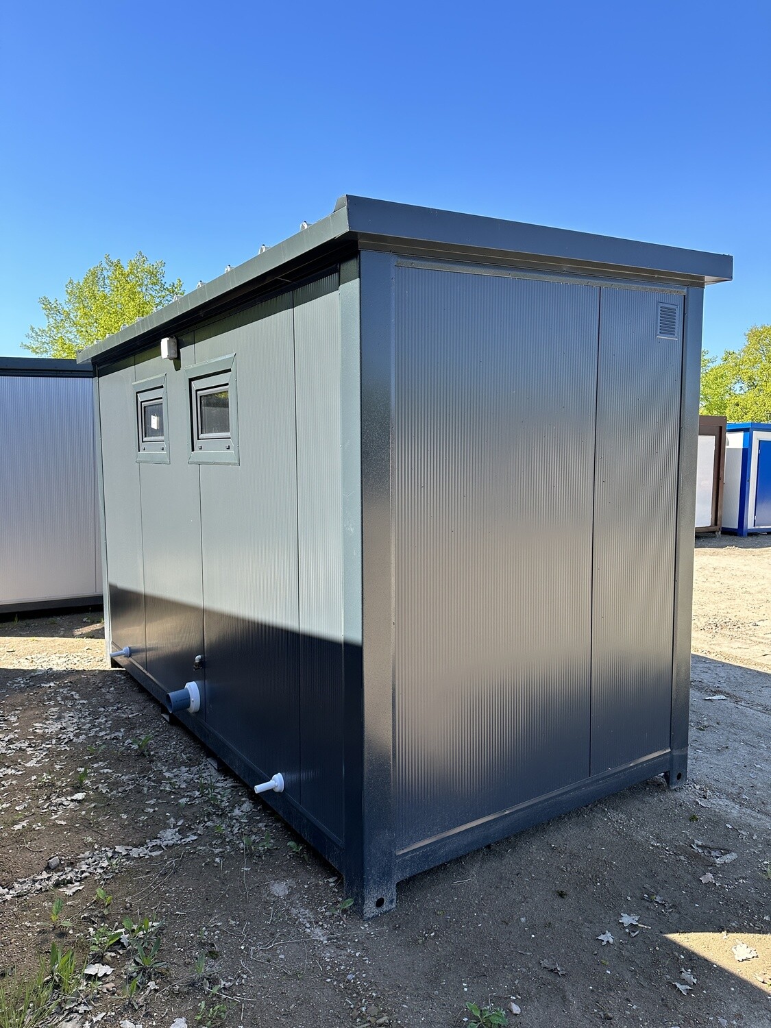 Seiten- und Rückansicht mit zwei kleinen Fenstern und den weißen Abwasserstutzen am unteren Rahmen