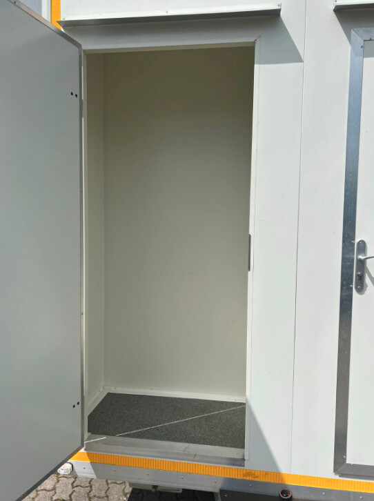 Geöffnete Tür mit Blick in einen leeren Vorraum mit dunklem Bodenbelag, außen orangefarbene Kantenleiste