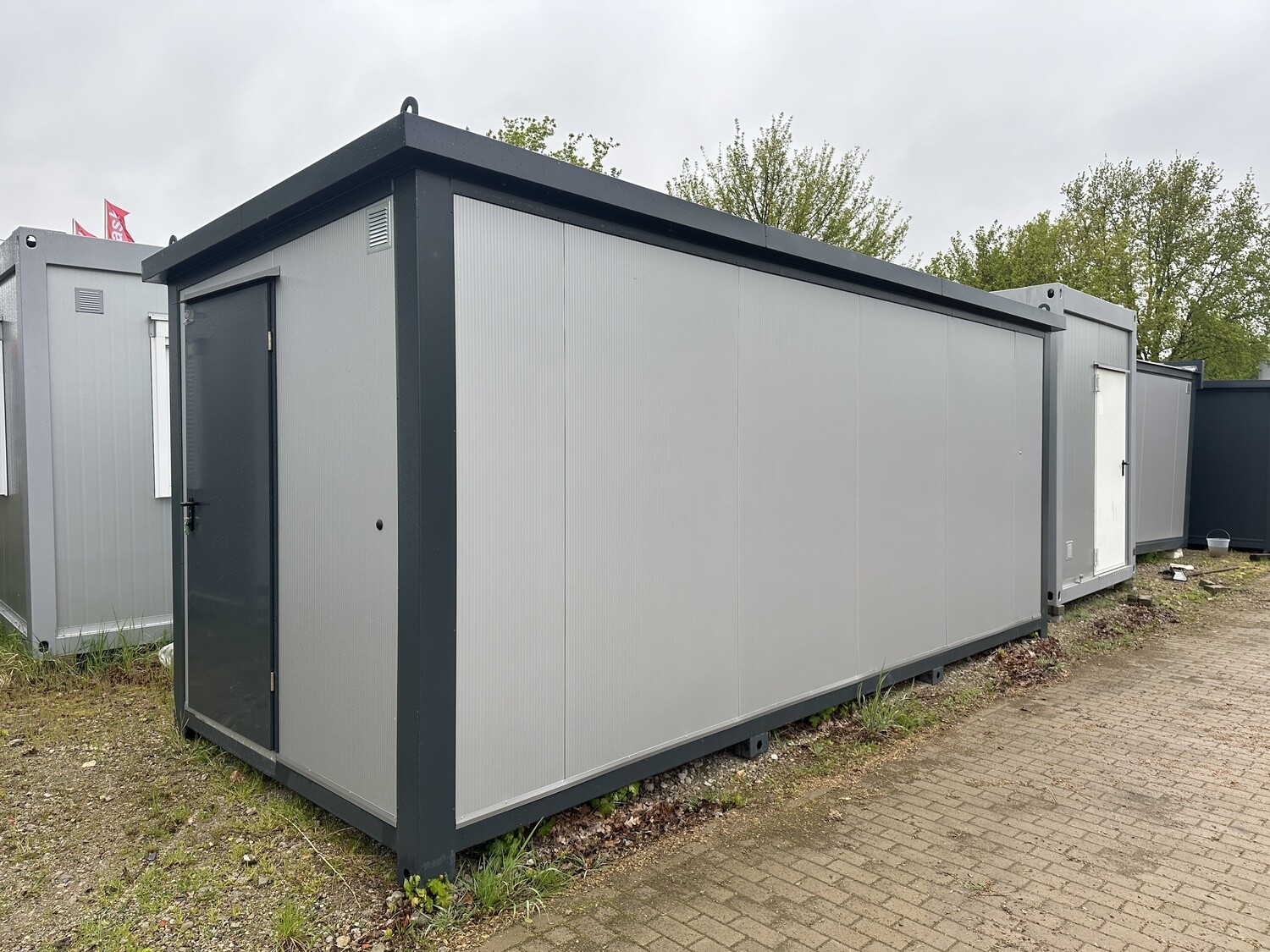Schräg von der Stirnseite aufgenommener Duschcontainer mit Eingangstür und Kranösen an den Ecken
