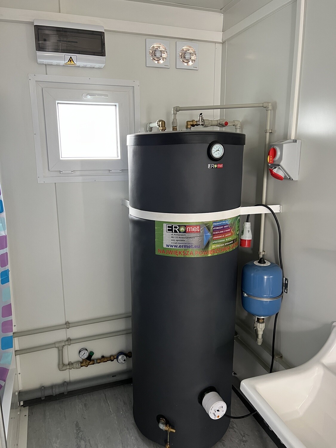 Detailaufnahme des Warmwasserspeichers mit Sicherungskasten, Ausdehnungsgefäß und Verrohrung