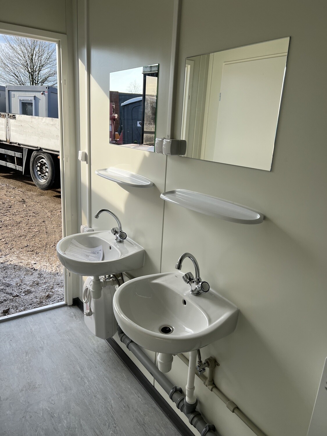 Waschbereich des WC-Containers mit zwei Becken, Spiegeln, Ablagen und Untertisch-Warmwassergerät
