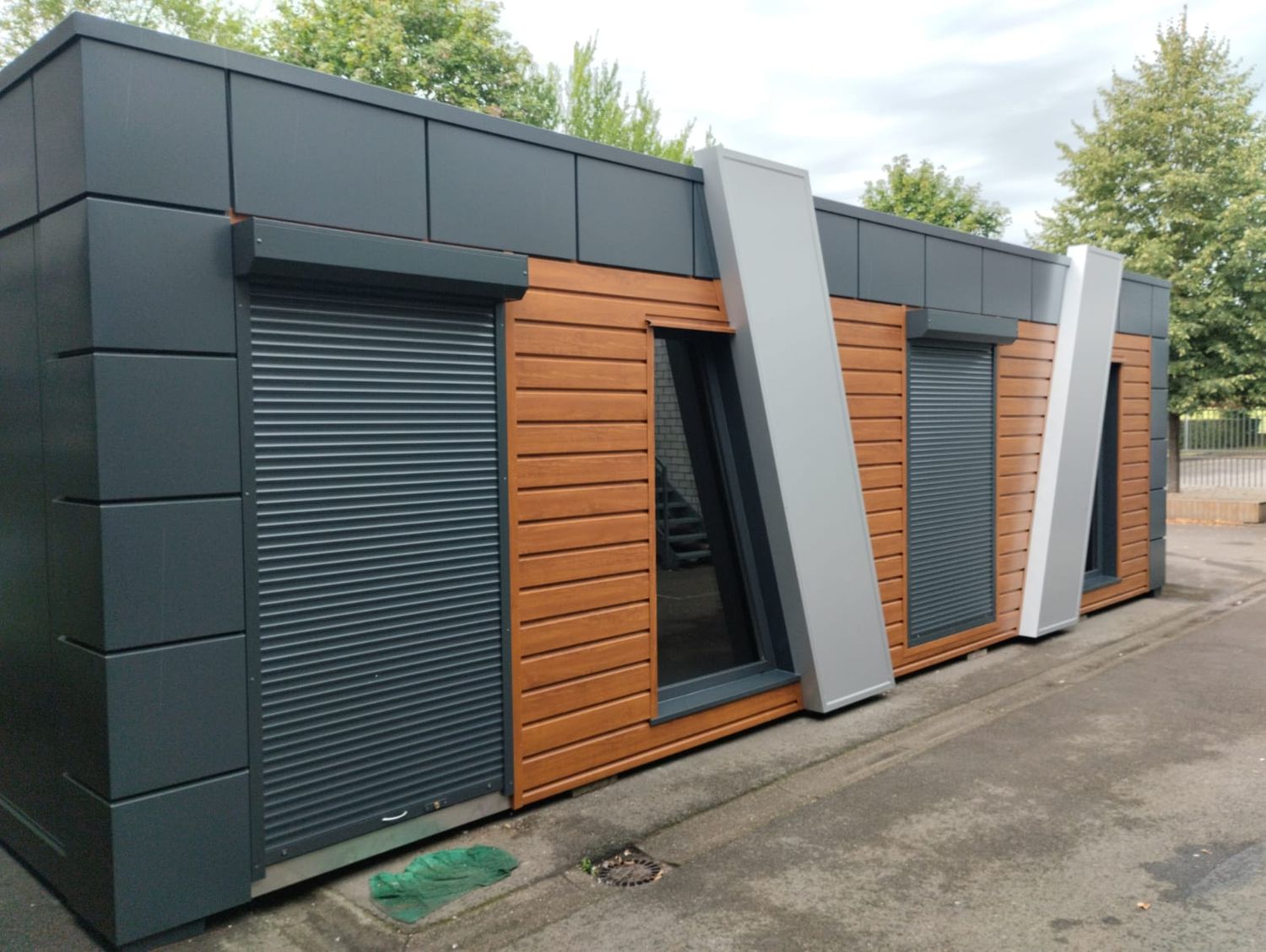 Seitlich aufgenommen: Typ Dublin mit heruntergelassenen Rollläden vor Tür und Fenstern, Fassade anthrazit