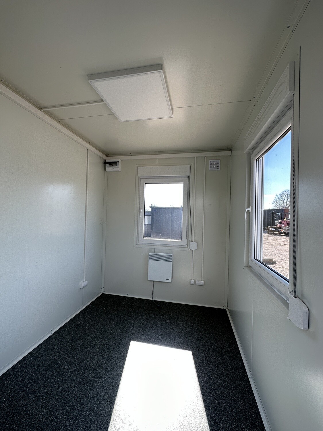 Innenansicht des Bürocontainers 3,00 x 2,44 mit Wandheizgerät unter dem Fenster und LED-Deckenleuchte