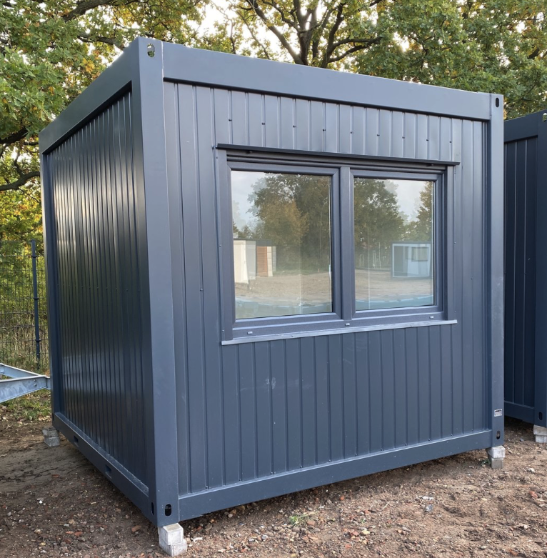 Anthrazitfarbener Bürocontainer 3,00 x 3,00 m mit breitem Doppelfenster, aufgeständert auf Bodenplatten