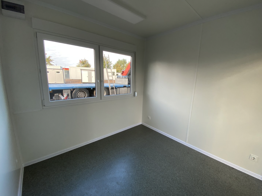 Leerer Innenraum mit Doppelfenster, hellen Wandpaneelen und grauem Boden, Bürocontainer 3,00 x 3,00 m
