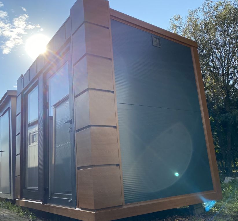 Schrägansicht im Gegenlicht: geschlossener Rollladen und Holzoptik-Verkleidung, Bürocontainer 3,20 x 2,10 m