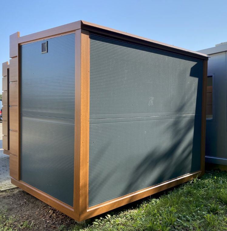 Längsseite mit heruntergelassenem Rollladen und Lüftungsgitter, Bürocontainer 3,20 x 2,10 m auf Rasen