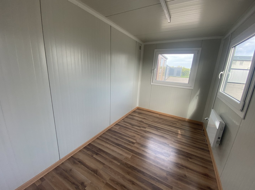 Blick in die Ecke des Bürocontainers 4,00 x 2,20 m mit Fenster, Wandpaneelen und Heizgerät am Boden