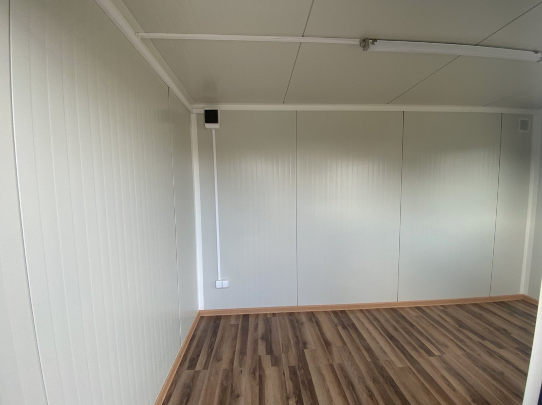 Helle Wandverkleidung mit Aufputzsteckdose und Leitungsführung im Bürocontainer 4,00 x 2,20 m