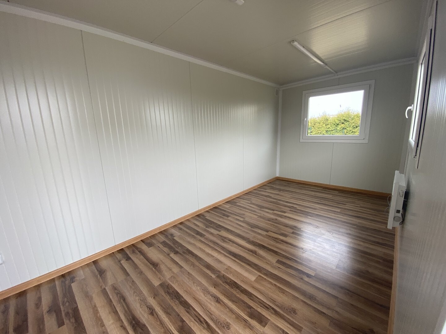 Helle Wandpaneele und Laminatoptik im Bürocontainer 5,00 x 2,40 m, Fenster und Heizgerät rechts