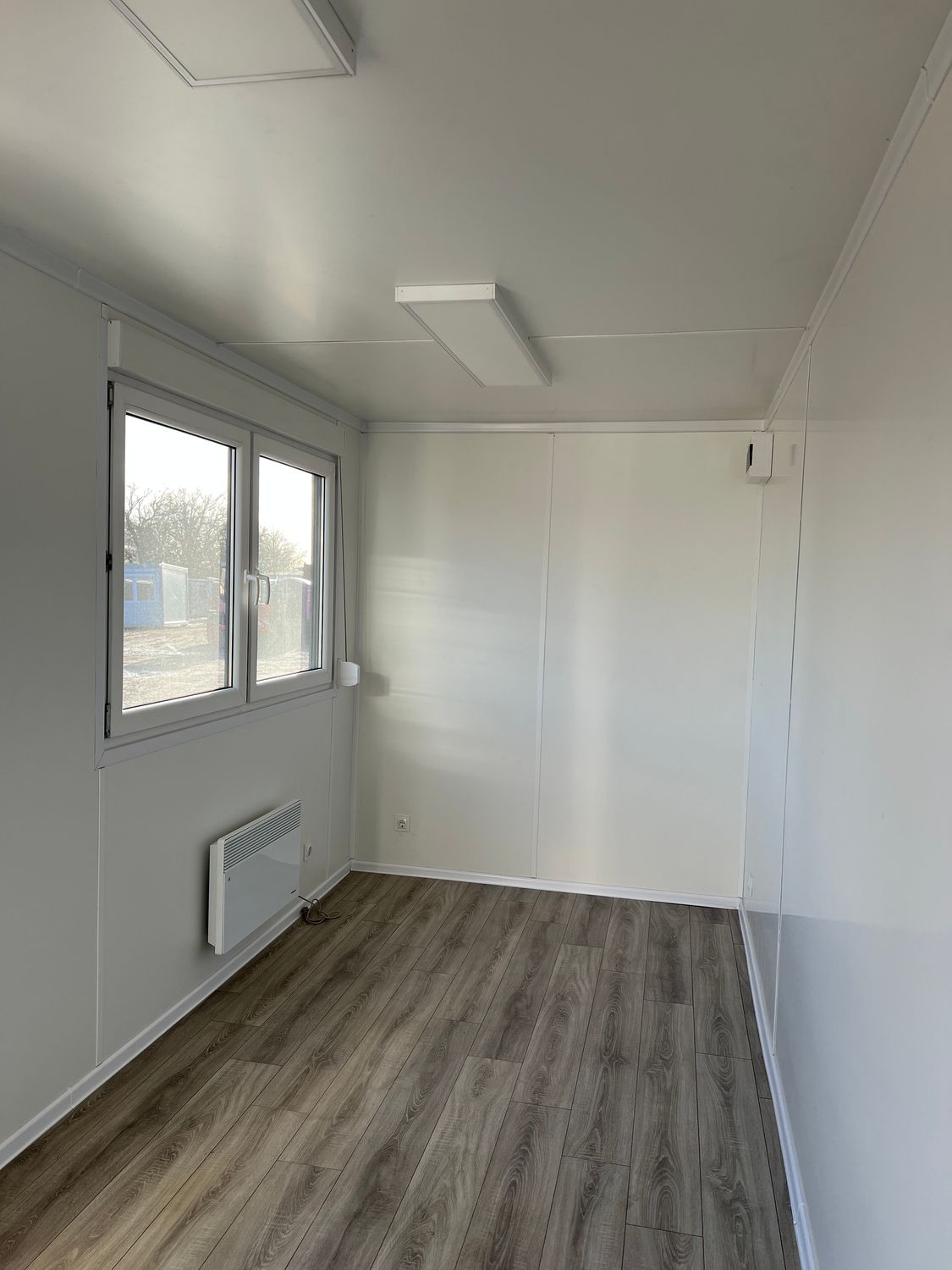 Innenansicht in Weiß mit LED-Deckenpanelen, Fenster und Wandheizgerät, Bürocontainer 6,00 x 2,44
