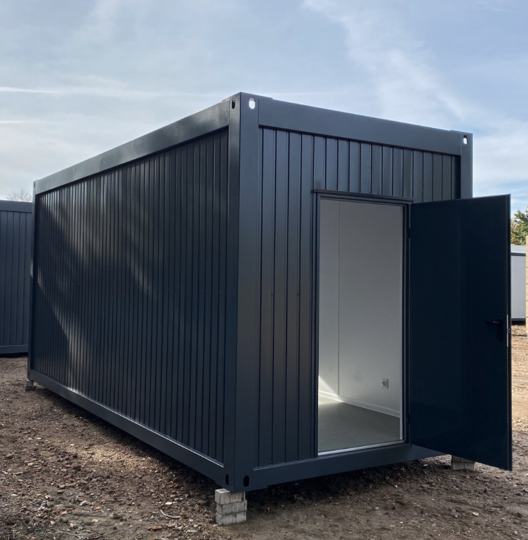 Geöffnete Stirnwandtür gibt den Blick in den hell verkleideten Innenraum des Bürocontainers frei