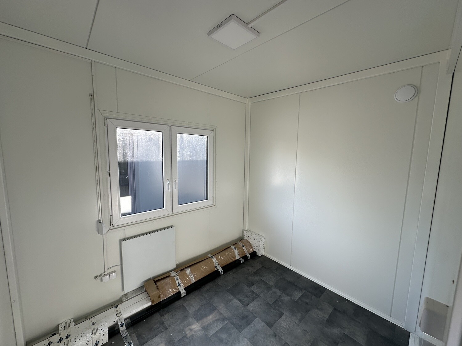 Innenraum der Tromsø im Ausbau: weiße Wände, Fenster mit Heizkörper und grauer Fliesenboden