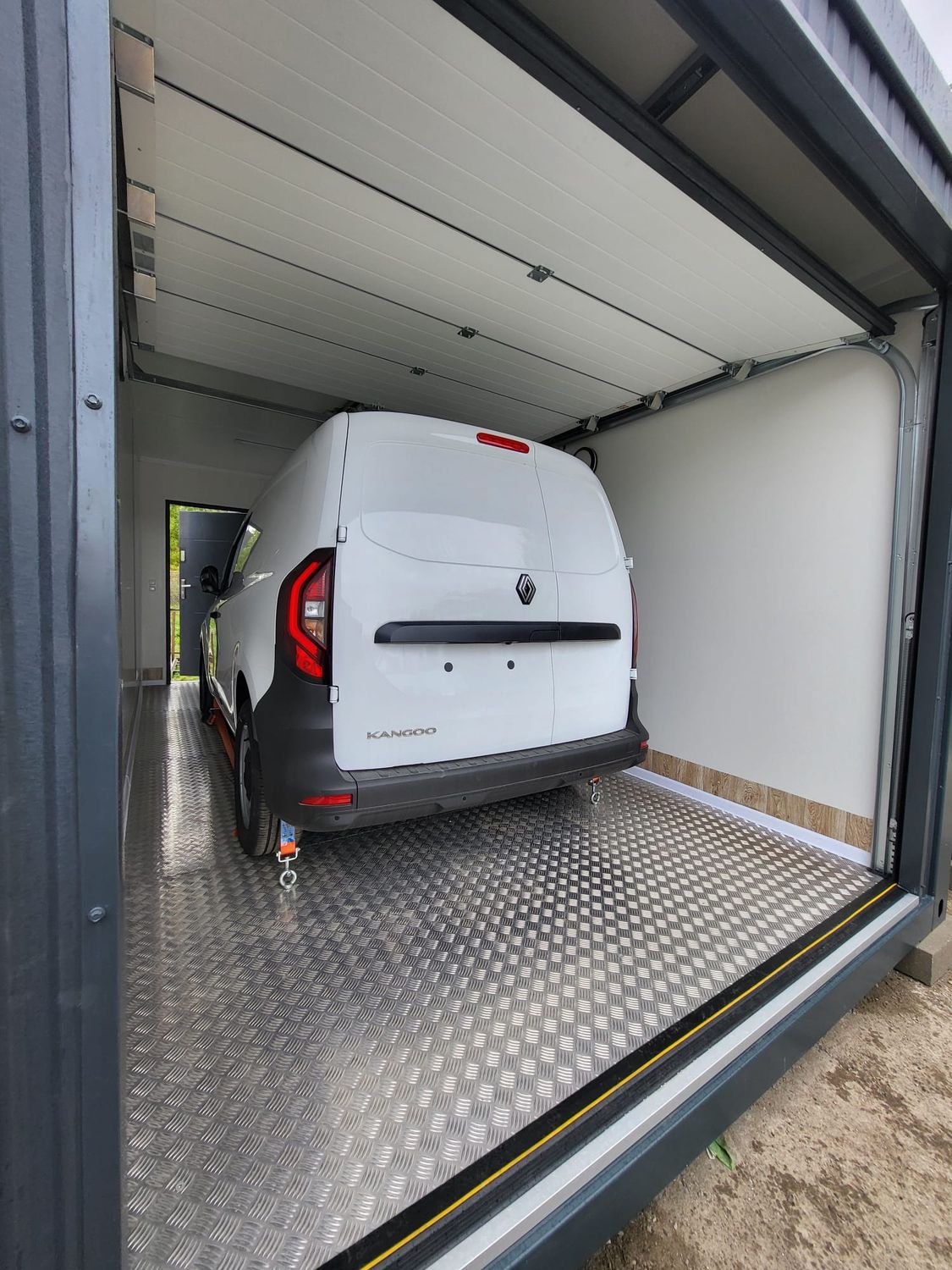 Innenansicht mit eingeparktem Kastenwagen auf Riffelblechboden und geöffnetem Sektionaltor