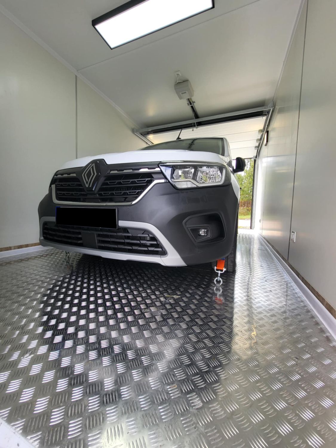 Fahrzeugfront im Garagencontainer, darüber LED-Panel und Torantrieb an der hellen Decke