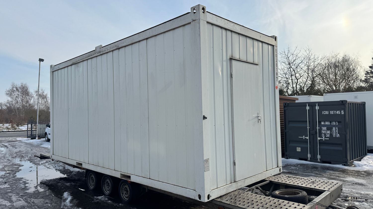 Seitenansicht mit Stirnwandtür des Mannschaftscontainers 20’ auf dem Anhänger im Hof