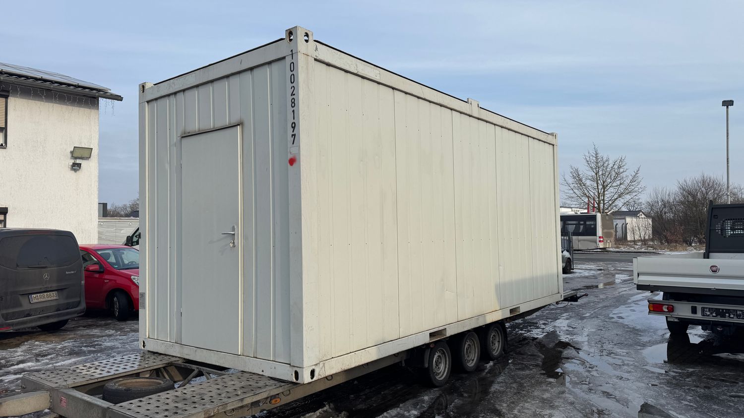 Geschlossene Längsseite und Eingangstür des Bürocontainers 20’, abgestellt auf dem Anhänger