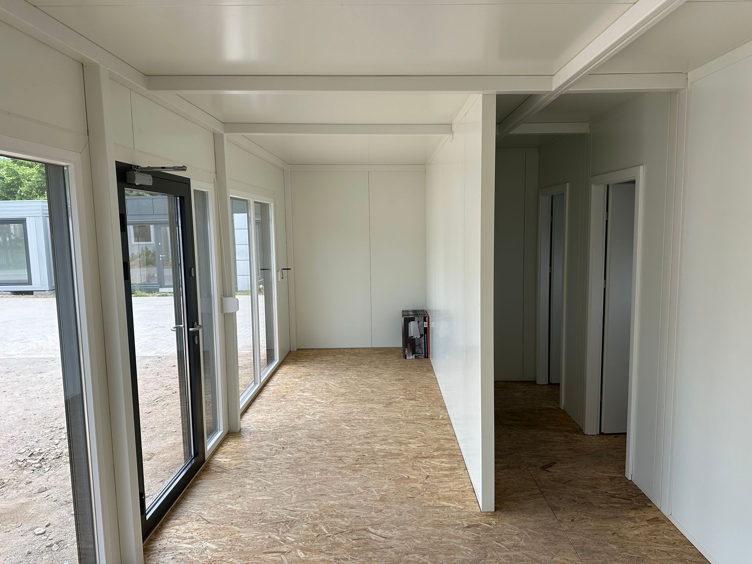 Blick durch den leeren Verkaufsraum auf die Trennwände und zwei Innentüren des Imbisscontainers