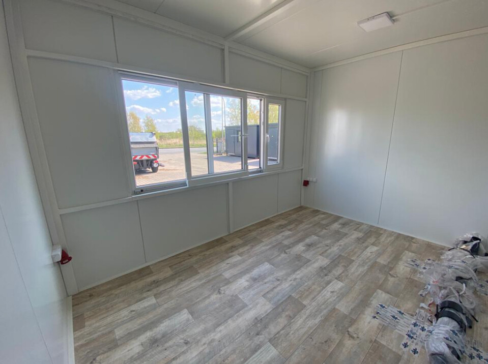 Verkaufsfenster von innen mit Blick auf den Hof, helle Wandverkleidung und Holzoptikboden