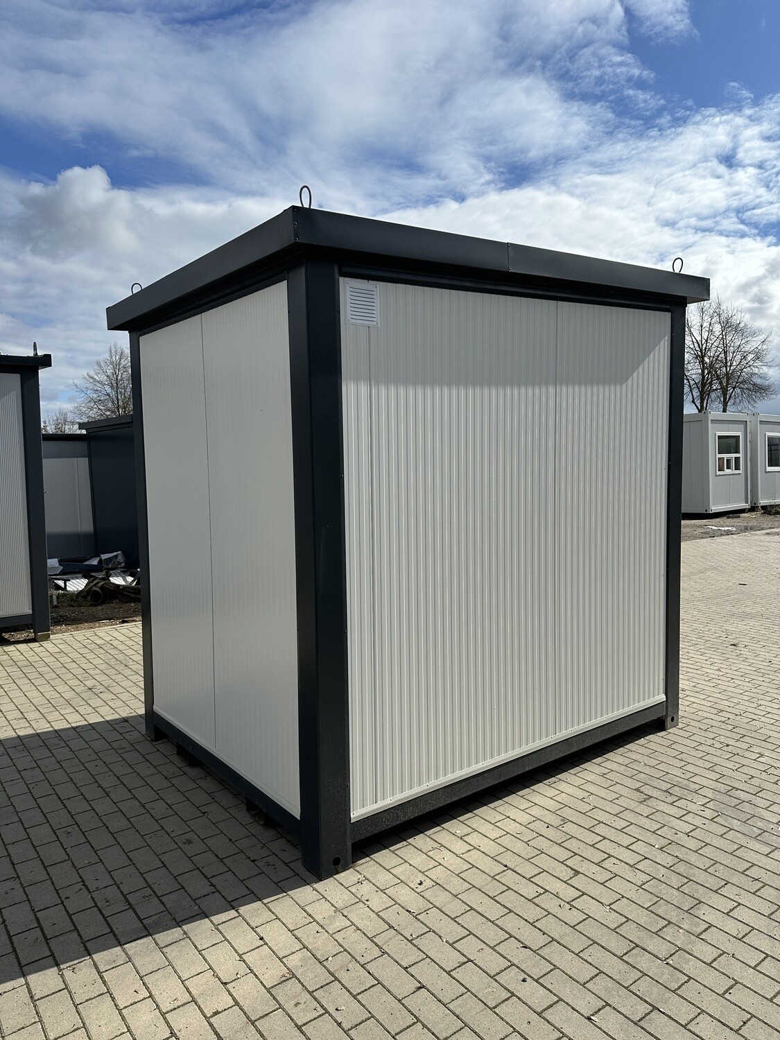 Rückansicht mit geschlossenen weißen Wandpaneelen, Lüftungsgitter und Kranösen am Dachrahmen