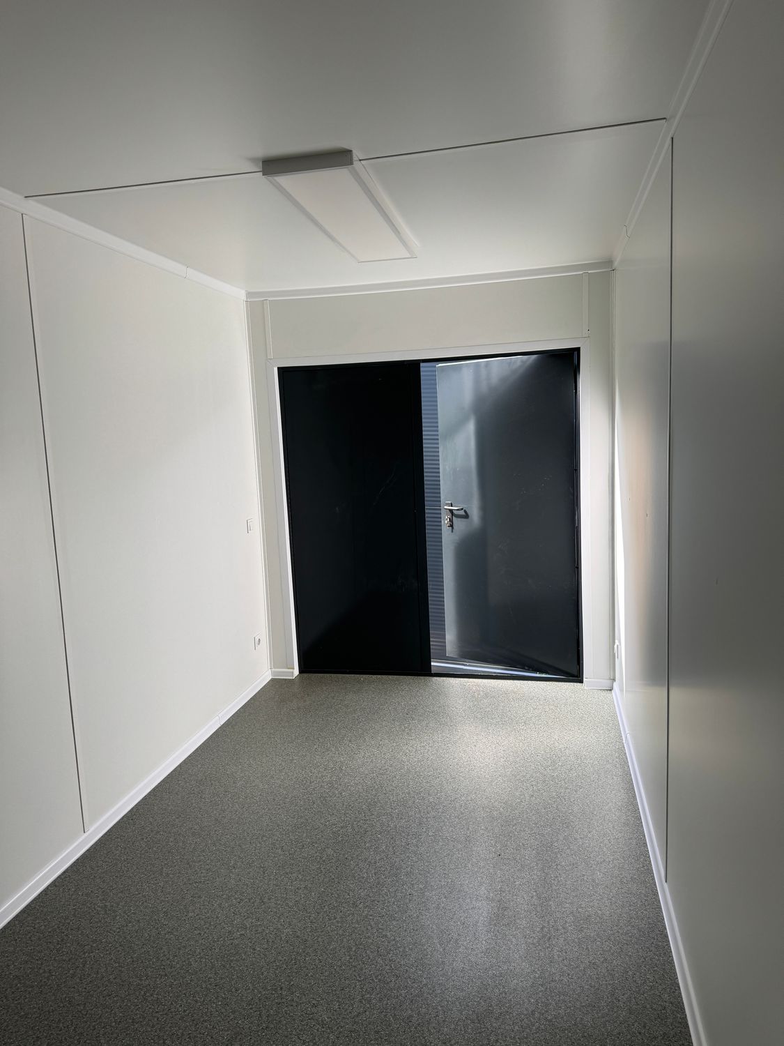 Blick durch den Innenraum auf die geschlossene zweiflügelige Tür des Lagercontainers 6,00 x 2,44