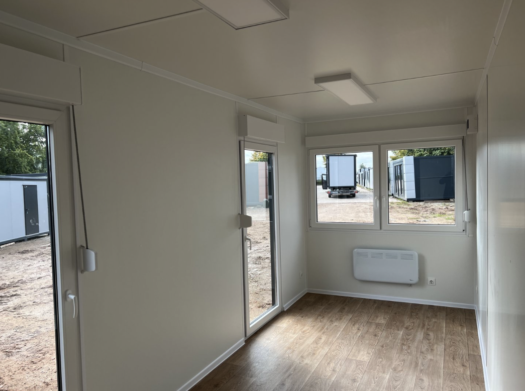 Innenansicht des leeren Büroraums mit Fenster, Wandkonvektor, LED-Deckenleuchte und Laminatboden