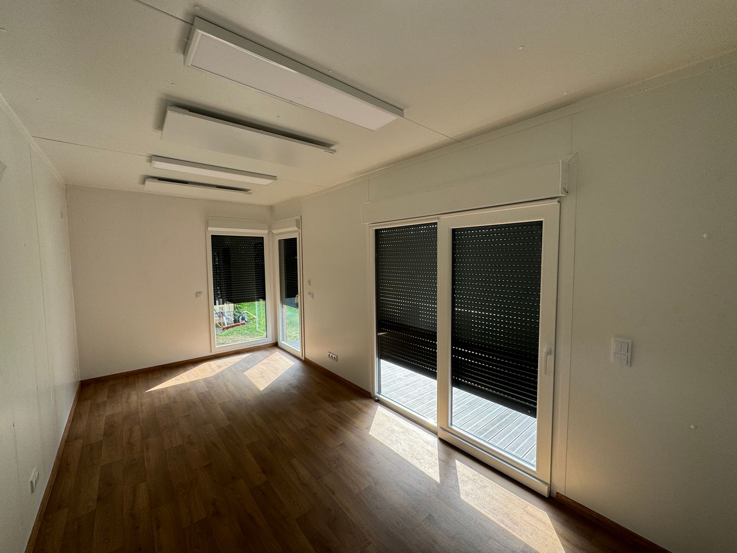 Innenansicht mit Laminatboden, Deckenpaneelen und Schiebetür zur Terrasse im Premium Tiny House