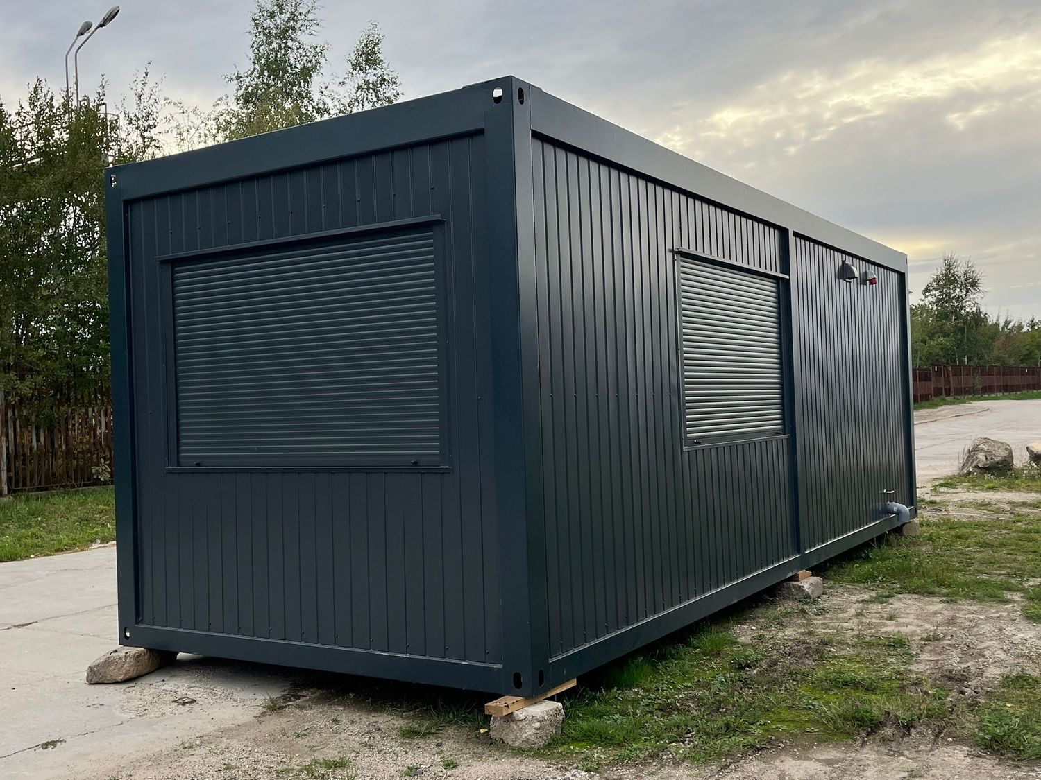 Seitenansicht mit geschlossenen Rollläden vor beiden Fenstern des Premium Wohncontainers