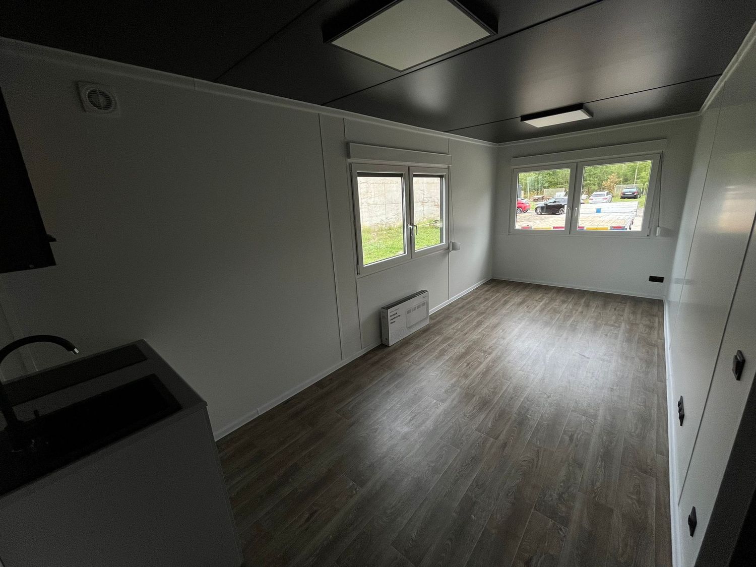 Blick vom Küchenbereich in den Wohnraum mit zwei Fenstern und Heizkörper unter dem Fenster