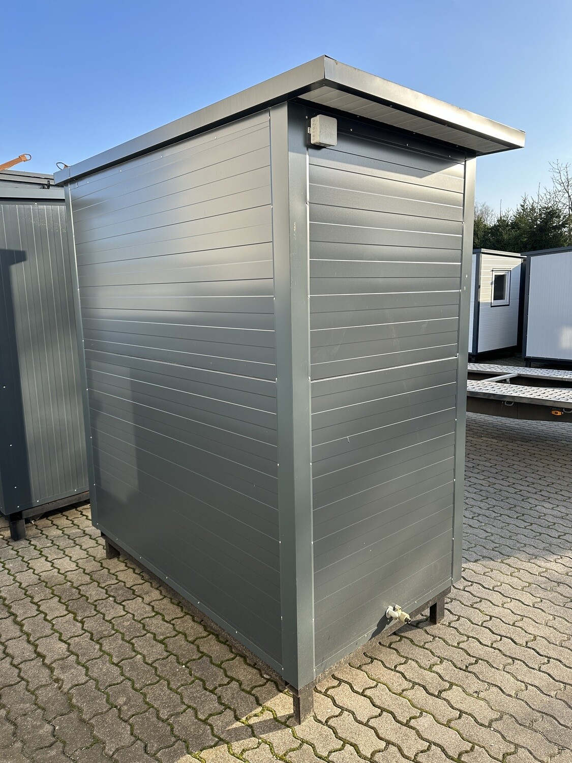 Graue Seitenansicht mit Dachüberstand, Abzweigdose und Ablaufanschluss am Sanitärcontainer 2,00 x 1,15 m