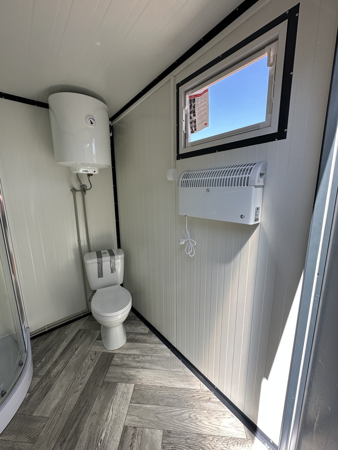 Innenansicht mit WC, Boiler, Wandkonvektor und Fenster im Sanitärcontainer 2,00 x 2,00 m
