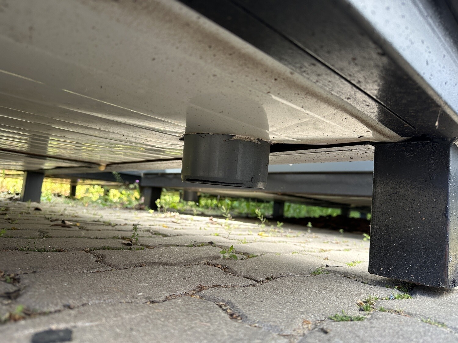 Detailaufnahme von unten mit Abflussrohr und Stahlfuß unter dem Sanitärcontainer 2,00 x 2,00 m