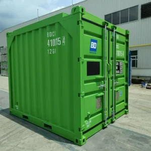 Grüne Ausführung des 10-Fuß-Offshore-Containers mit geschlossener Türseite vor einer Werkshalle