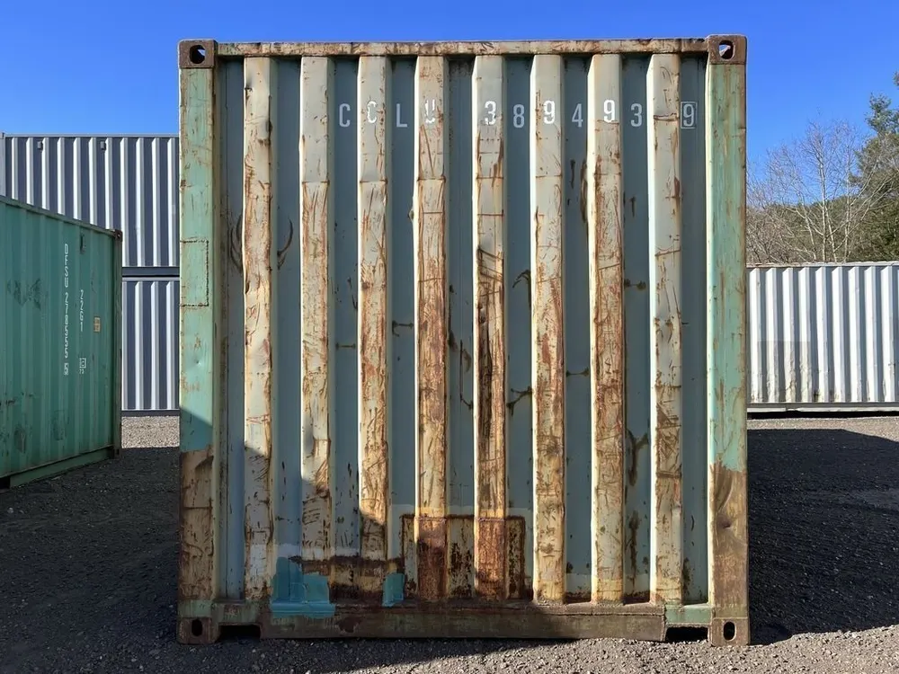 Geschlossene Stirnwand mit Wellprofil, Rostfahnen und aufgesprühter Nummer, daneben weitere Container