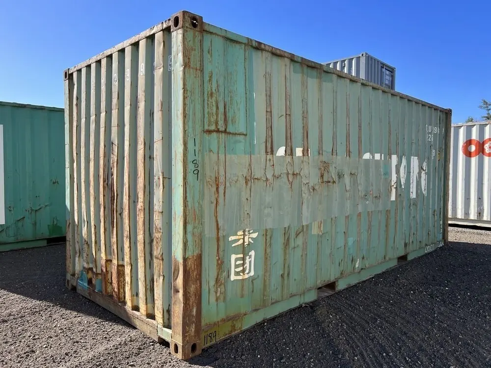 Rückwand und Längsseite im Halbprofil, aufgestellt zwischen weiteren Containern auf einem Schotterplatz