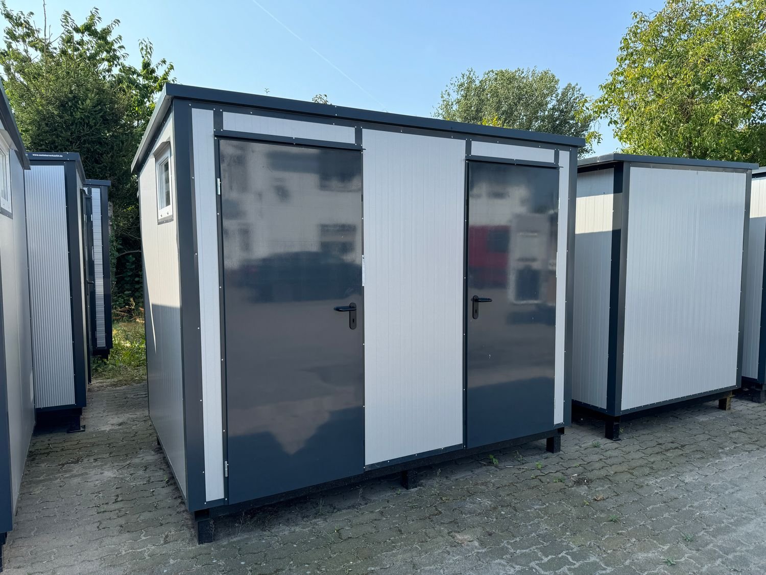 Außenansicht des 3,00 x 2,00 m Doppel-WC Containers mit zwei grauen Türen und Fenster an der Stirnseite