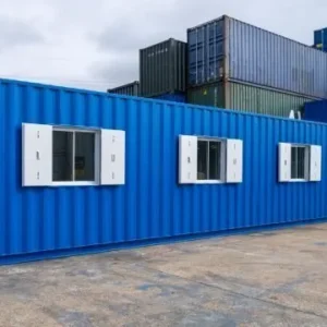 Blauer 40-Fuß-Bürocontainer als mobile Büroeinheit mit drei weißen Fenstern im Containerlager