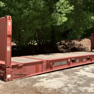 Rotbrauner 40-Fuß-Flatrack-Container mit hochgestellten Stirnwänden und Holzdeck, vor Bäumen