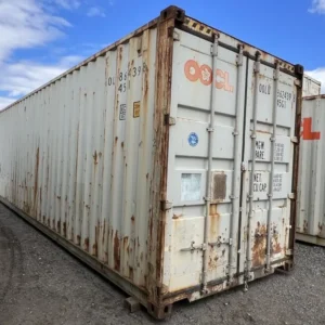 Schrägansicht des 40-Fuß-High-Cube-Containers mit geschlossenen Türen, Rostschlieren und Kiesuntergrund