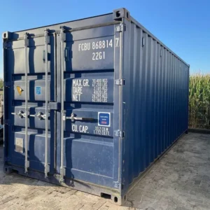 Dunkelblauer Seecontainer im Freien vor einem Maisfeld, Türseite mit Verriegelungsstangen