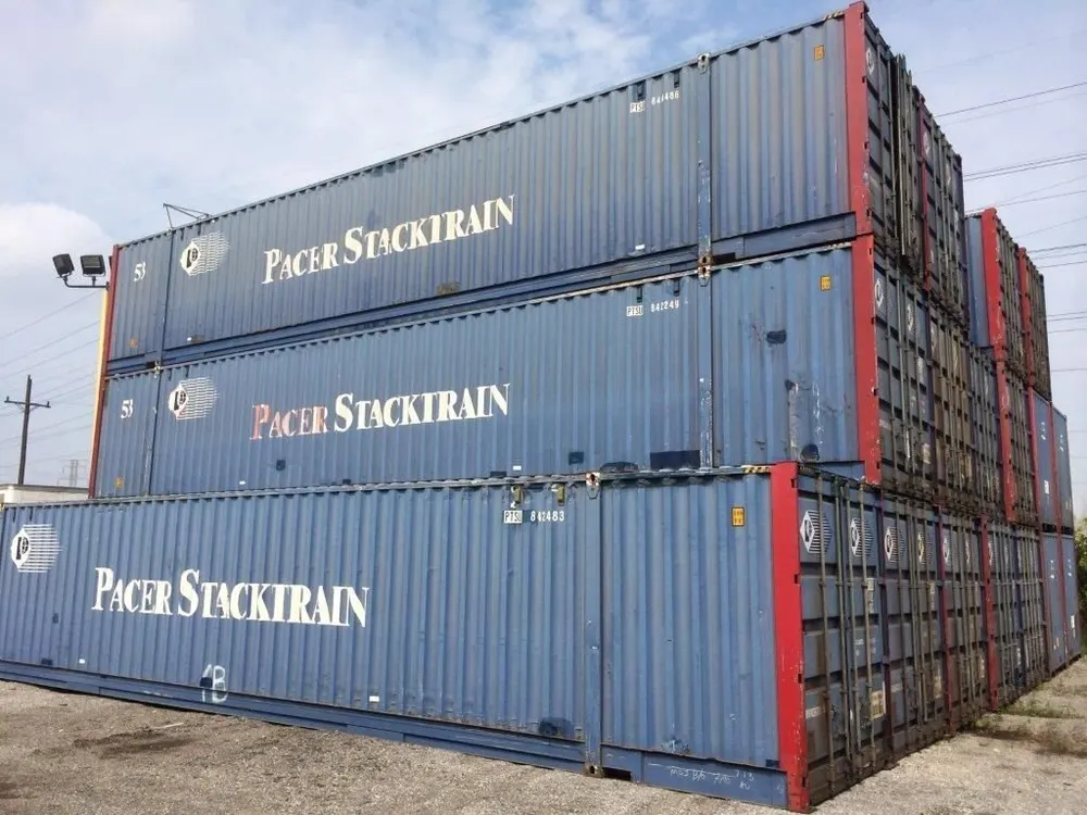 Mehrere 53-Fuß-Container mit Aufdruck PACER STACKTRAIN gestapelt, blaue Wände und rote Eckpfosten