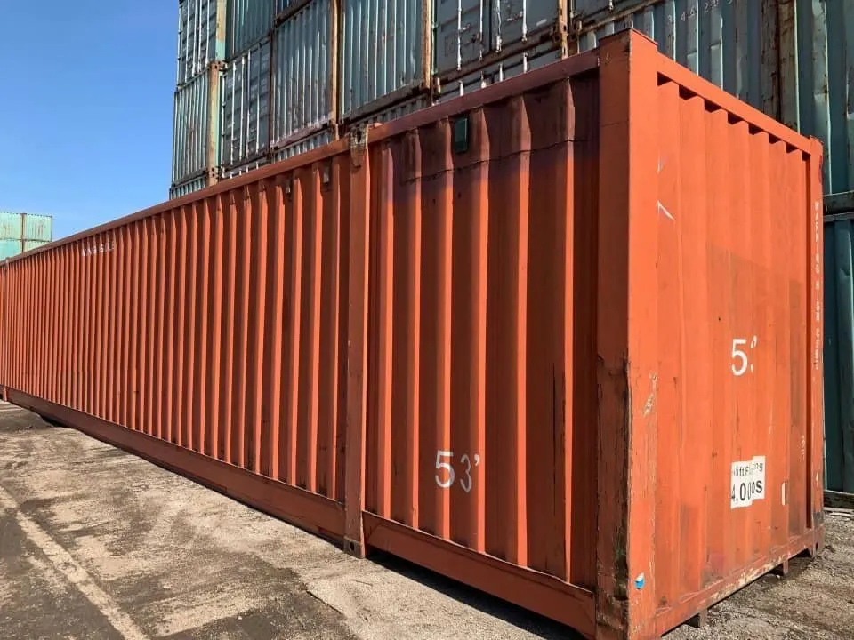 Orangeroter 53-Fuß-Seecontainer zwischen gestapelten Einheiten, Wellblechwand mit Farbabplatzungen