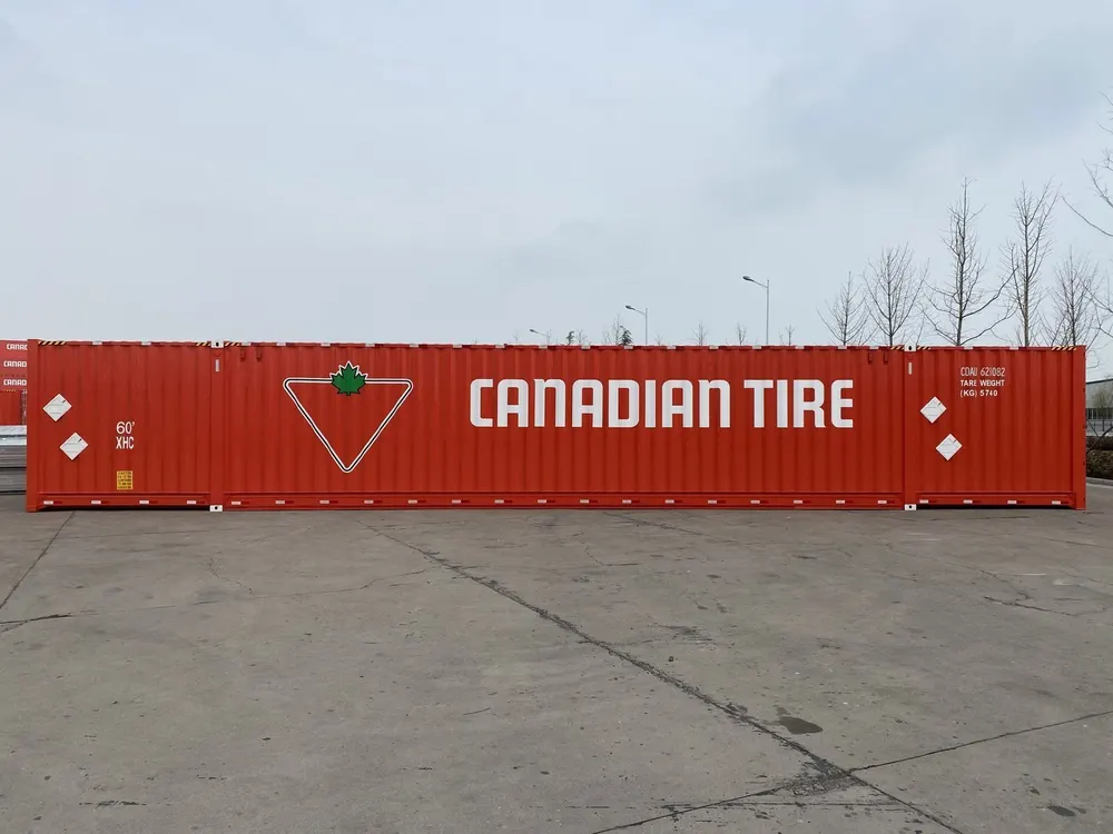 Lange rote Wandseite des Überlängen-Containers auf befestigtem Hof, im Hintergrund kahle Bäume