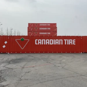 Seitenansicht des roten 60-Fuß-Seecontainers mit Canadian-Tire-Schriftzug, dahinter gestapelte Einheiten