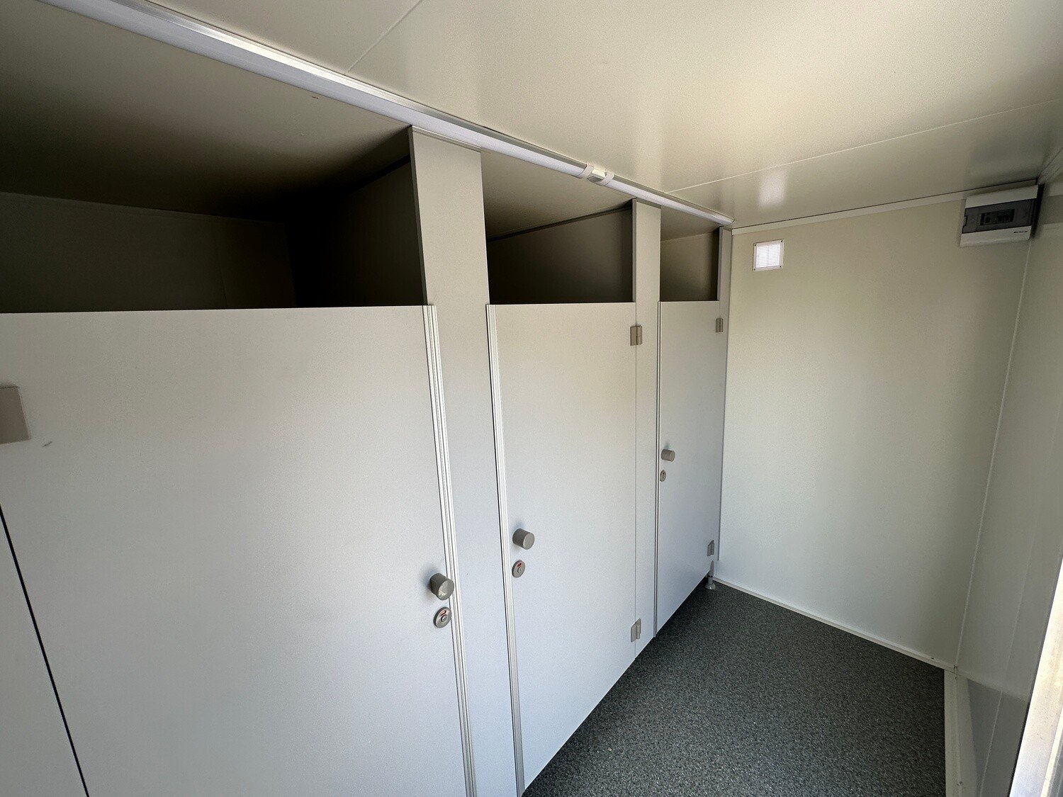 Drei nebeneinanderliegende Toilettenkabinen mit Drehknaufverriegelung im WC-Anhänger für Damen